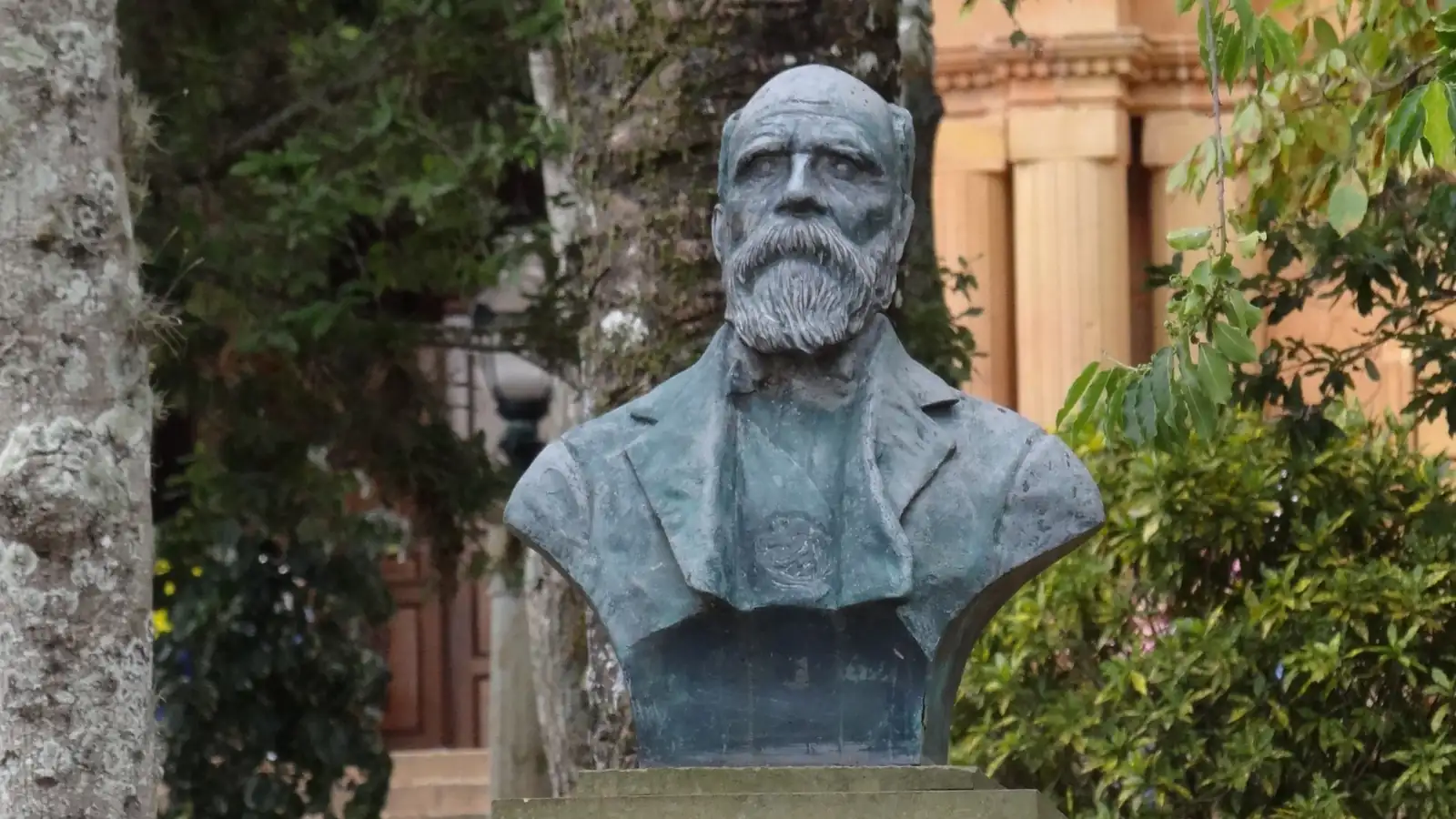 Busto de Aquileo Parra, de barba larga, sobre un pedestal de piedra en el parque principal de Barichara, entre árboles