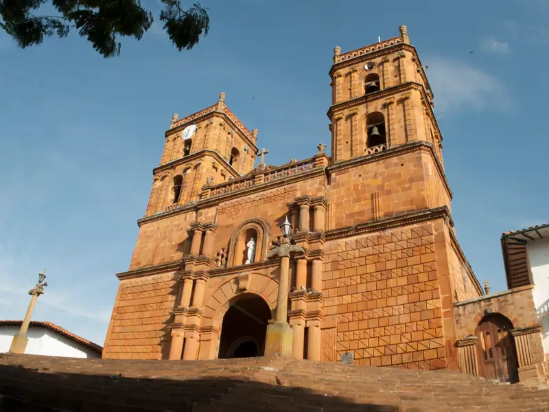 Fachada de piedra labrada del templo, con sus dos torres de campanario, una imagen blanca en el nicho sobre la puerta y la escalinata delante