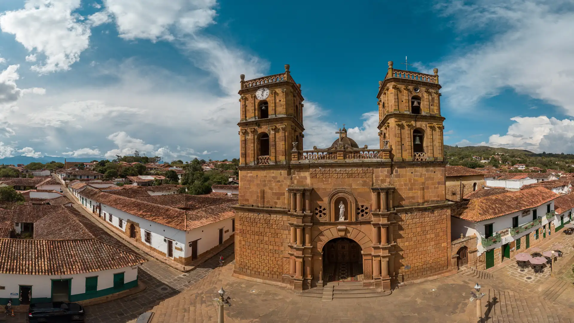 Templo de piedra de Barichara con sus dos torres y su escalinata, entre las calles y los techos de teja del pueblo, visto desde el aire