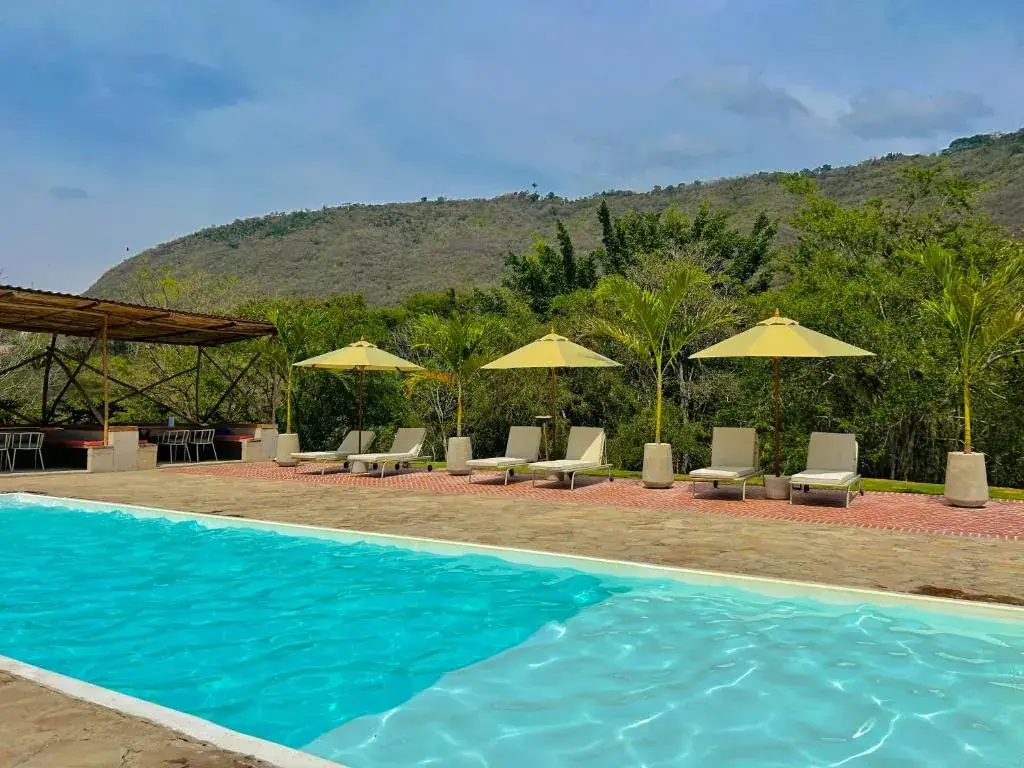 Piscina climatizada de Del Río con tumbonas y parasoles al pie de la montaña, en San Gil