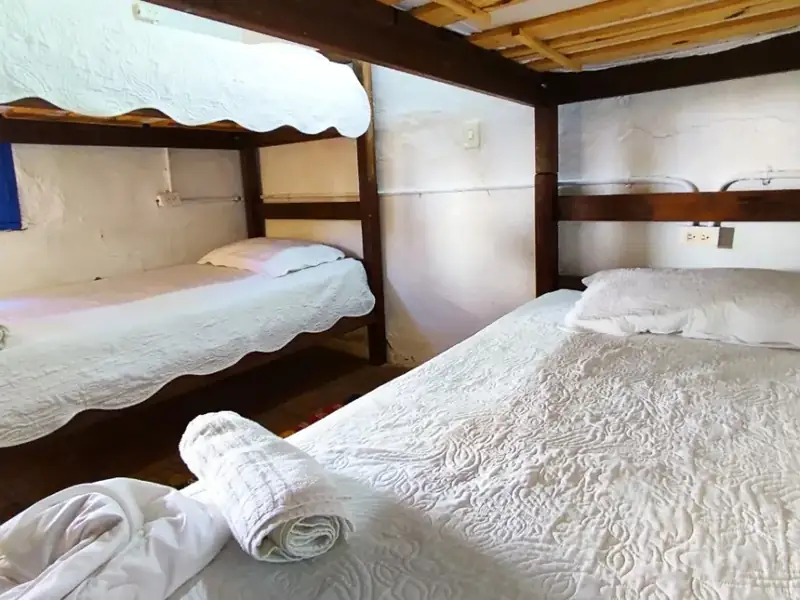 Literas de madera tendidas, con toallas enrolladas, en el dormitorio compartido
