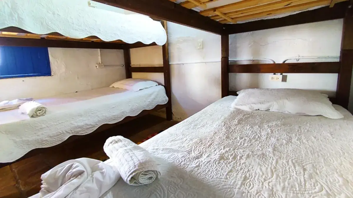 Literas de madera tendidas, con toallas enrolladas, en el dormitorio compartido