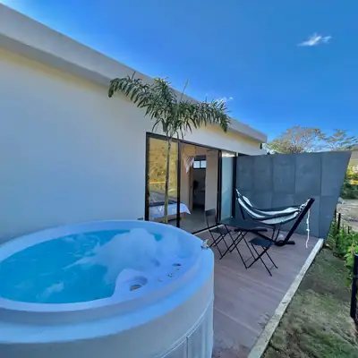 Burbujas en el jacuzzi del Glamping Deluxe; al fondo, la hamaca negra, una palma y el ventanal de la cabaña