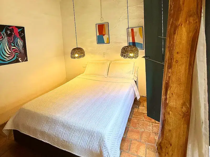 Habitación Doble de paredes blancas con cama queen, lámparas de fibra y viga de madera a la vista