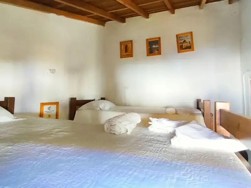 Habitación Familiar de paredes blancas, ropa de cama blanca, tres cuadros pequeños y techo de madera