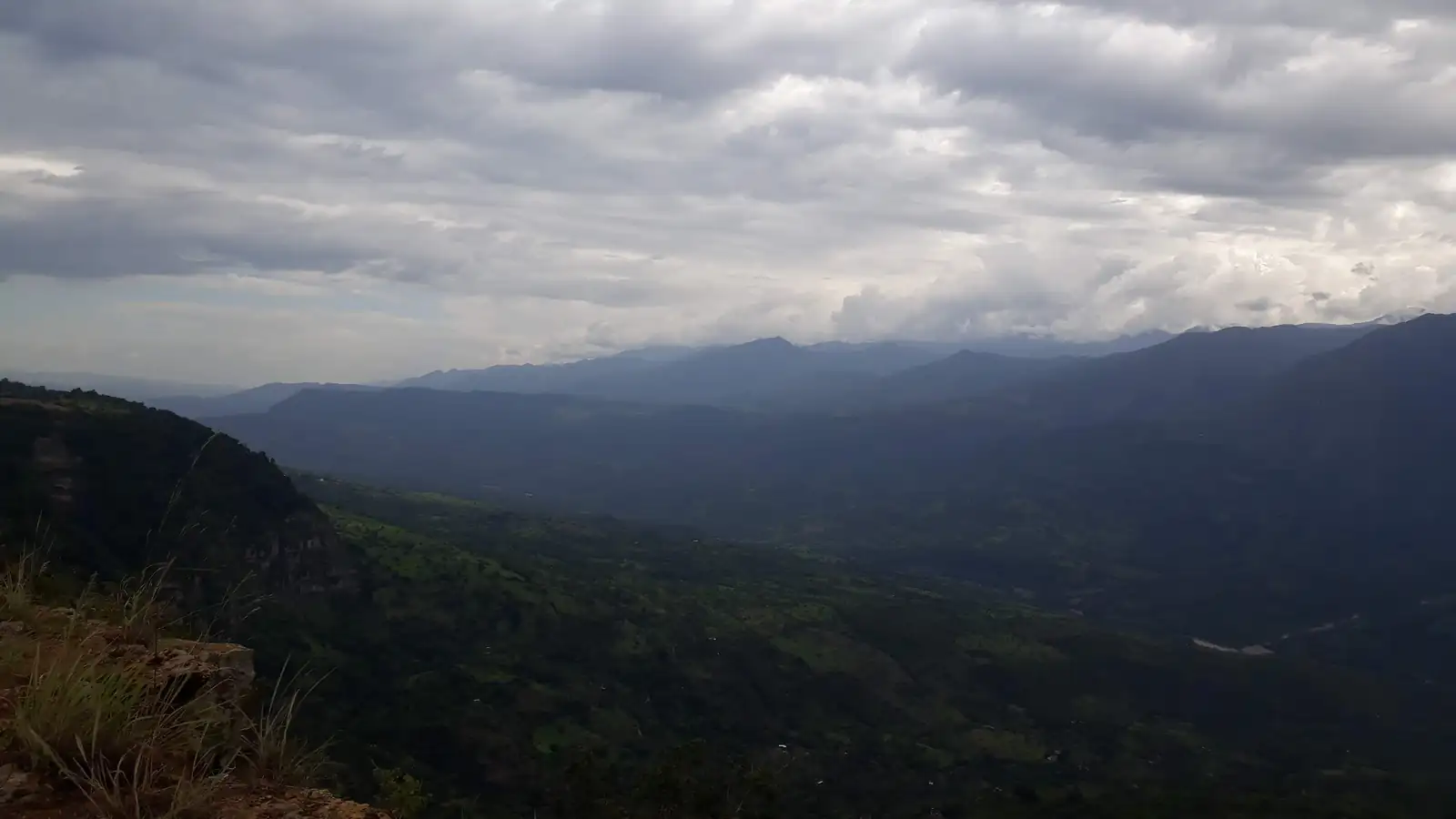 Nubes grises sobre el cañón del río Suárez y sus montañas, desde el borde de roca y pasto seco del Salto del Mico