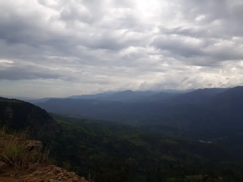Nubes grises sobre el cañón del río Suárez y sus montañas, desde el borde de roca y pasto seco del Salto del Mico